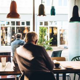 Older man sitting inside of a coffee shop.