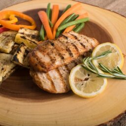 Grilled chicken with vegetables on a yellow dinner plate.